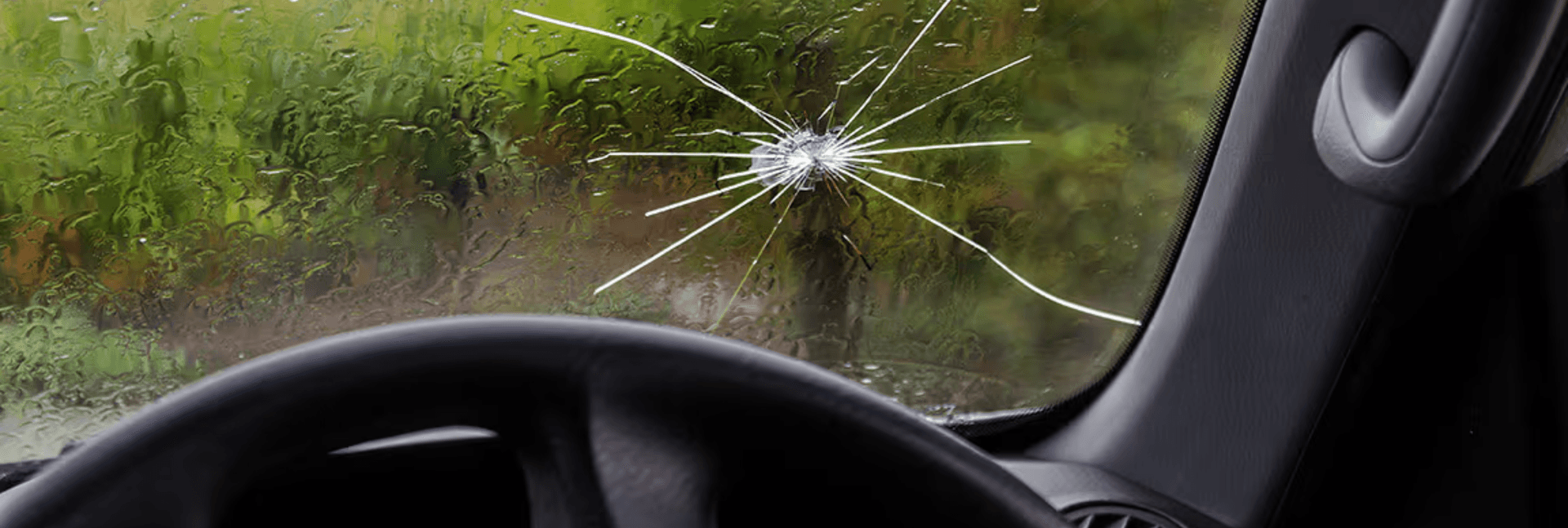 The inside view of a spider-cracked windshield in the rain.