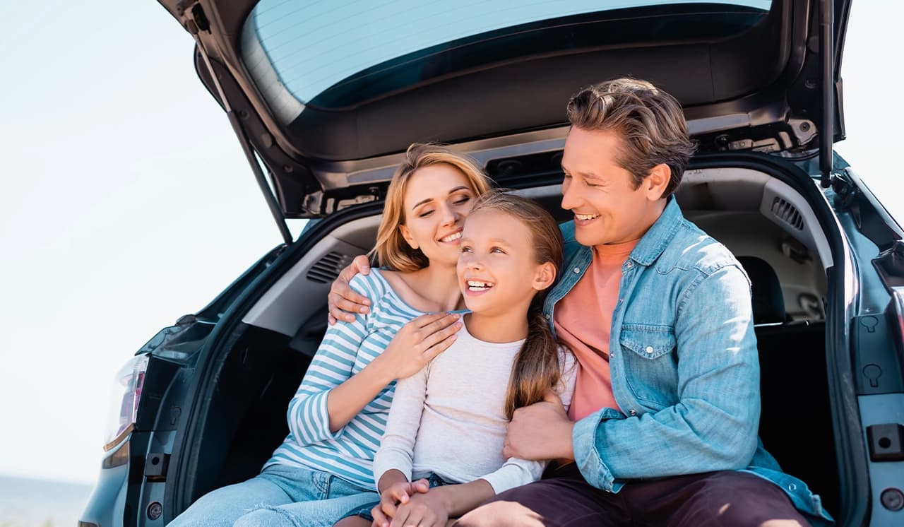 Smiling family sitting in an open tailgate