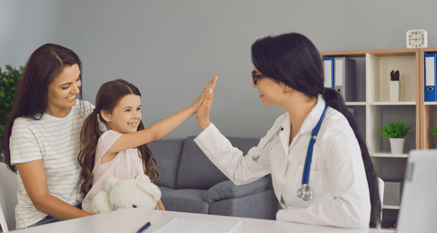 Mother and daughter seeing doctor with the daughter giving the doctor a high-five.